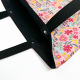 Lined tote bag measuring approximately 12" wide x 14" tall x 2.5" deep. Exterior fabric features bright and cheery pink floral background with the words of the Hail Mary interspersed throughout. Black lining. Black cotton webbing straps.