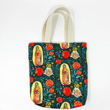 Fully-lined tote bag measuring approximately 8" wide, 9.5" tall, and 2.5" deep. Vibrant multicolored floral print with images of Our Lady of Guadalupe and St. Juan Diego.  Off-white lining. Natural cotton webbing straps.