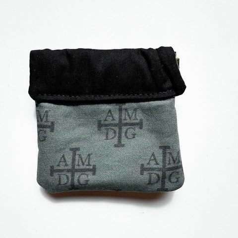 Clasp pouch measuring approximately 3.75” wide x 3.5” wall x 1” deep. Outer fabric is a Dark green background with black AMDG images. Inside lining is a black fabric. Clasp frame for easy opening and closing.