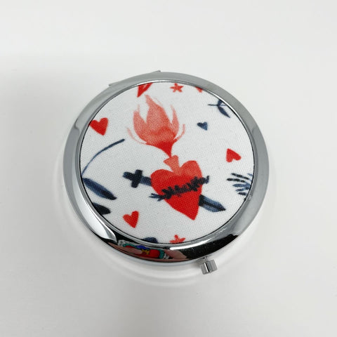 Blue and red watercolor floral pattern with Sacred Heart images scattered throughout; silver 1-compartment pill box with mirror