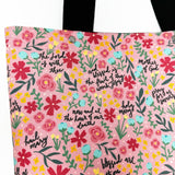 Lined tote bag measuring approximately 12" wide x 14" tall x 2.5" deep. Exterior fabric features bright and cheery pink floral background with the words of the Hail Mary interspersed throughout. Black lining. Black cotton webbing straps.