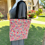 Lined tote bag measuring approximately 12" wide x 14" tall x 2.5" deep. Exterior fabric features bright and cheery pink floral background with the words of the Hail Mary interspersed throughout. Black lining. Black cotton webbing straps.