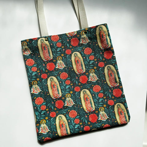 Unlined tote bag measuring approximately 13” wide x 15” tall. Exterior fabric features vibrant multicolored floral print with images of Our Lady of Guadalupe and St. Juan Diego. Natural cotton webbing straps.