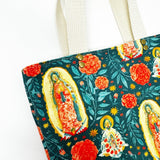 Fully-lined tote bag measuring approximately 8" wide, 9.5" tall, and 2.5" deep. Vibrant multicolored floral print with images of Our Lady of Guadalupe and St. Juan Diego.  Off-white lining. Natural cotton webbing straps.